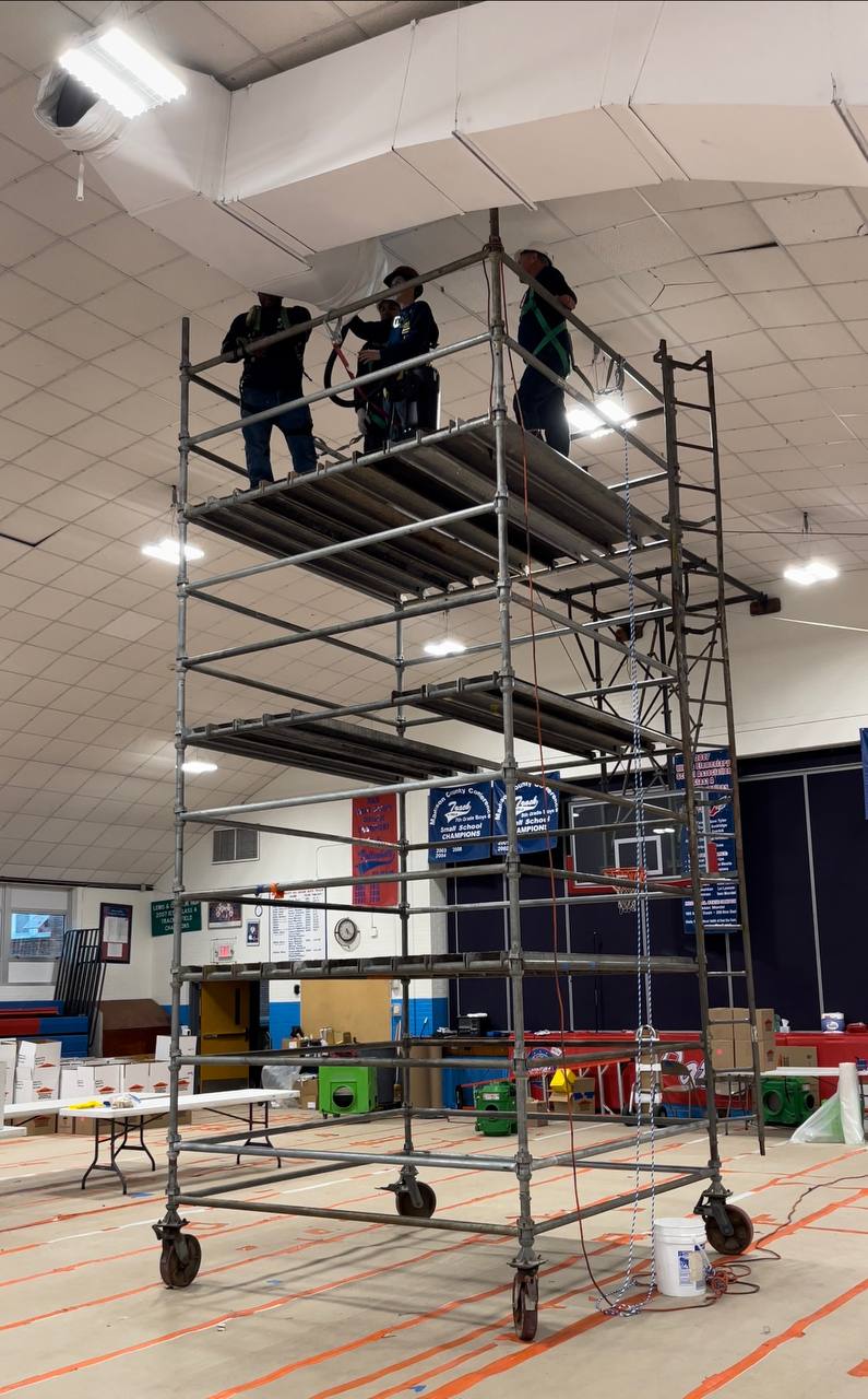 AH-CHOO crew on scaffolding cleaning school gymnasium HVAC system